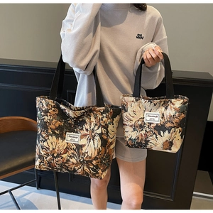 Close-up of small and large tote bags with floral patterns and woven black handles