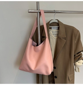 Pink large capacity faux leather hobo shoulder bag hanging in a stylish wardrobe setting