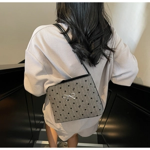 Detail of grey polka dot canvas shoulder bag with silver metallic bow and tiny patterns