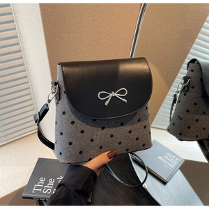 Détail d'un sac seau à pois avec breloque nœud en métal poli et rabat noir élégant