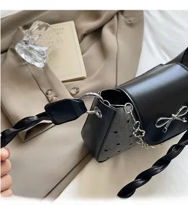 Detail of silver metal bow and black heart pattern on stylish leather shoulder bag
