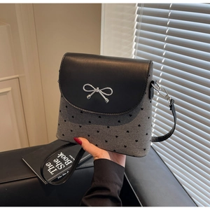 Détail du sac à nœud avec texture cœur grise et rabat élégant en cuir noir brillant
