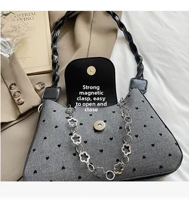 Detail of magnetic snap closure and heart pattern on textured denim shoulder bag