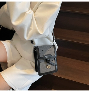 Détail du sac de téléphone en denim gris avec broderie cœur noir et pendentif en métal