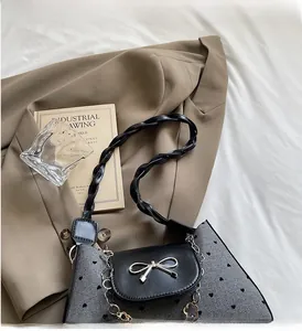 Detail of grey heart-patterned fabric underarm bag with silver bow buckle and woven strap
