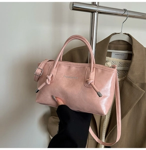 Détail d'un sac cabas en cuir rose avec poignée nouée et bandoulière réglable