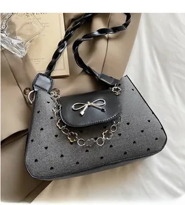 Detail of grey heart print bag with silver bow clasp and floral chain on soft fabric