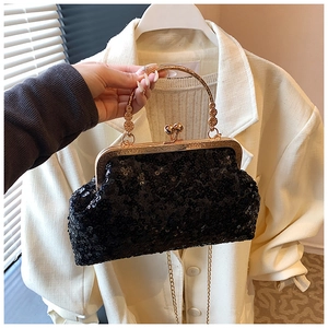 Detail of black sequined evening bag with gold metal handle and crossbody chain strap