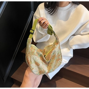 Detail of crescent canvas tote featuring floral jacquard fabric and green adjustable strap