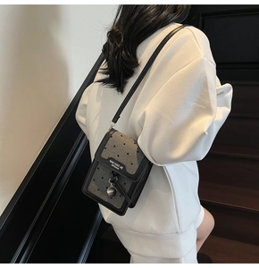 Détail du mini sac vertical avec texture perforée en cœur et fine bandoulière noire