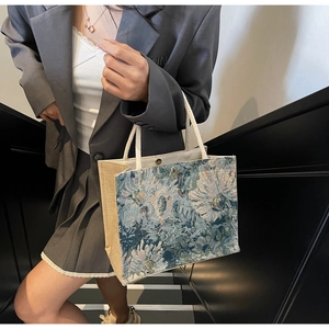 Detail of floral jacquard tote bag with white cotton rope handles and blue embroidery