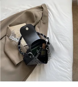 Detailed view of black underarm bag showing spacious interior with a notebook and perfume