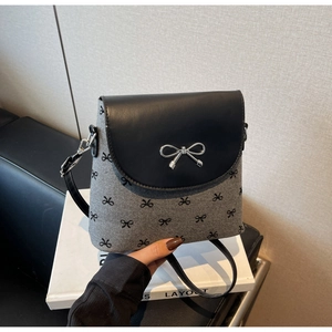 Détail du sac seau en tweed gris avec imprimés nœuds noirs et fermoir nœud argenté