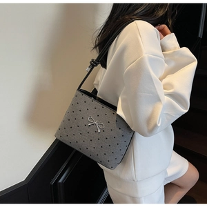 Close-up of grey heart-pattern canvas bag with silver bow ornament on shoulder strap