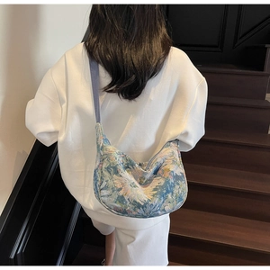 Detail of blue floral jacquard fabric and wide strap on crescent shoulder bag