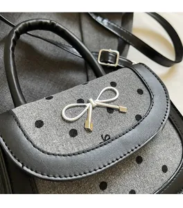 Close-up of gray polka dot fabric and silver metal bow clasp on a saddle bag