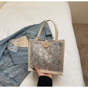 Detail of beige lace handbag with floral embroidery and natural wooden button closure