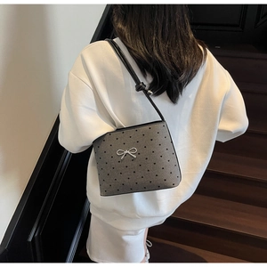 Detail of grey canvas crossbody bag featuring black heart patterns and a silver bow clasp