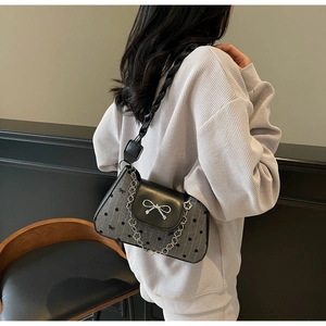 Detail of grey canvas underarm bag with black bow print and silver metallic buckle