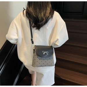 Détail du sac bandoulière avec texture à motifs de cœurs et boucle noeud argentée décorative