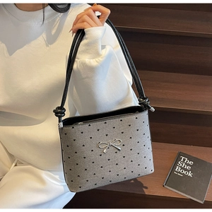 Close-up of grey canvas polka dot bag with silver bow accent and black leather strap