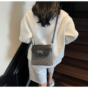 Détail d'un sac bandoulière chic avec boucle nœud argenté et broderie de cœurs