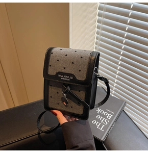 Détail du mini sac à téléphone vintage avec motif à cœurs gris et bordure en cuir noir