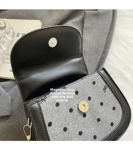 Detailed view of the convenient magnetic snap closure on the polka dot saddle bag