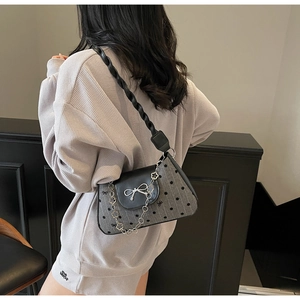 Detail of grey polka dot underarm bag with silver bow buckle and floral metal chain