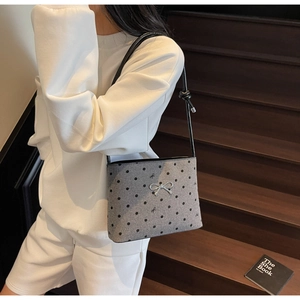 Detailed close-up of grey polka dot canvas bag with silver bow charm and embroidery