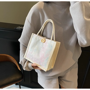 Close-up of white lace tote bag with floral print, button closure and braided rope handles