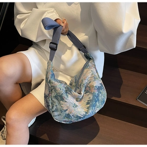 Detail of floral jacquard crescent bag with adjustable wide blue strap and zip closure