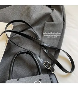 Detail of adjustable leather strap and silver buckle on grey polka dot baguette bag