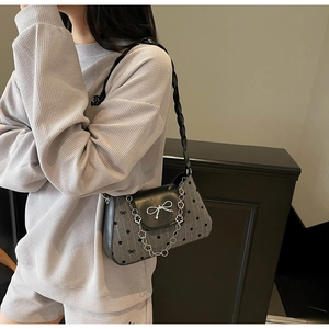 Detail of grey polka dot fabric underarm bag with silver flower chain and bow metal accent