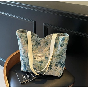 Close-up of vintage floral tapestry tote bag on a classic leather chair and book