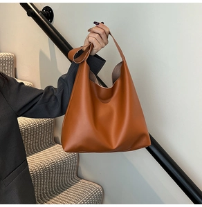 Close-up of minimalist caramel brown leather tote bag with wide shoulder strap design