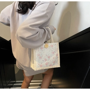 Detailed texture of a floral canvas handbag with a yellow button and white rope handle
