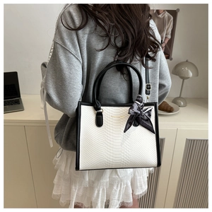 Close-up of white snakeskin texture tote bag with black handles and decorative scarf