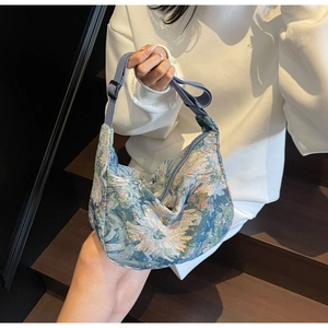 Detail of blue floral jacquard fabric texture and adjustable strap on crescent bag