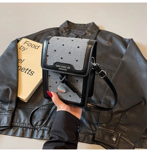 Détail du mini sac en denim gris avec motifs de cœurs noirs et bandoulière en cuir