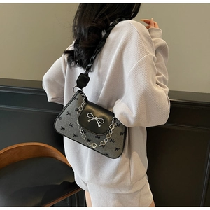 Detail of grey canvas shoulder bag with black bow print and silver metal buckle