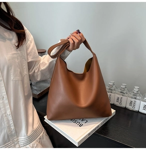 Detail of soft caramel leather tote bag with elegant draped texture and wide handles