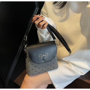 Détail du sac seau en tissu avec motif cœur et nœud argenté sur rabat en cuir