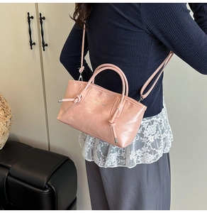Détail du sac cabas rose avec design à nœud latéral et logo sur cuir synthétique texturé