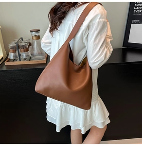 Brown large capacity tote bag worn by model in a minimalist modern interior