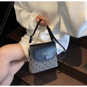 Vue détaillée du motif à pois et du nœud argenté sur un sac seau texturé