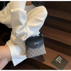 Détail du sac seau gris à pois avec rabat noir et décoration de nœud en métal argenté