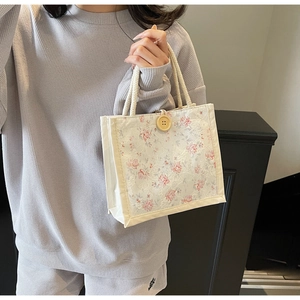 Detail of floral lace canvas handbag with wooden button and braided cotton rope handles