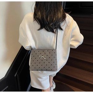 Detailed close-up of a retro polka dot crossbody bag with a silver bow on a gray fabric