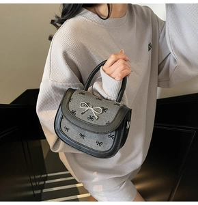 Close-up of grey saddle bag with black bow prints and silver metallic butterfly clasp